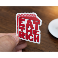 Sticker with red, stylized text in the shape of a slice of cake on a white background which reads Eat The Rich