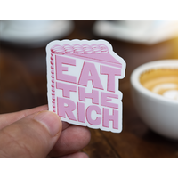 Sticker with pink stylized text in the shape of a slice of cake on a white background which reads Eat The Rich