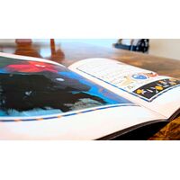 Close-up photograph of an open copy of the zine sitting on a wood table.