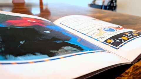 Close-up photograph of an open copy of the zine sitting on a wood table.