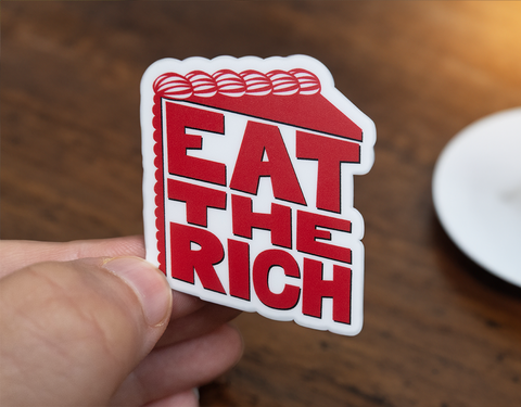 Sticker with red, stylized text in the shape of a slice of cake on a white background which reads Eat The Rich