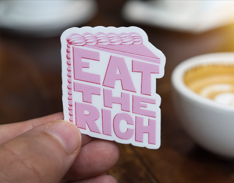 Sticker with pink stylized text in the shape of a slice of cake on a white background which reads Eat The Rich