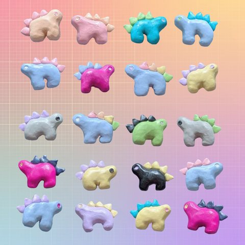 20 pride flag-themed stegosaurus charms set up in five rows of four against a gridded, pastel rainbow background. Featured flags are rainbow, lesbian, achillean, bisexual, pansexual, trans, nonbinary, genderfluid, intersex, asexual, and aromantic.